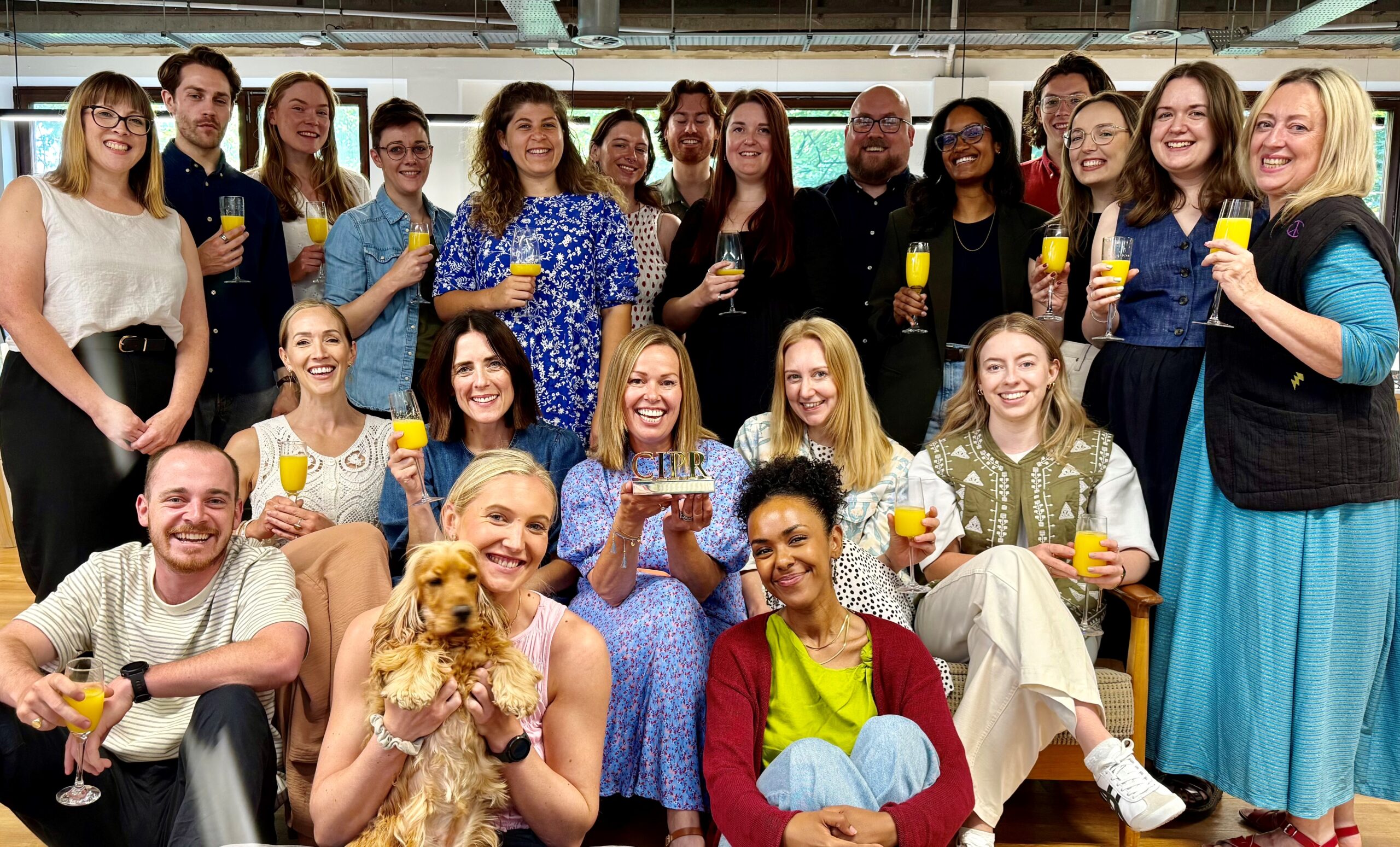 A photo of the Cowshed team celebrating the CIPR win. And a golden cocker spaniel. And bucks fizz.