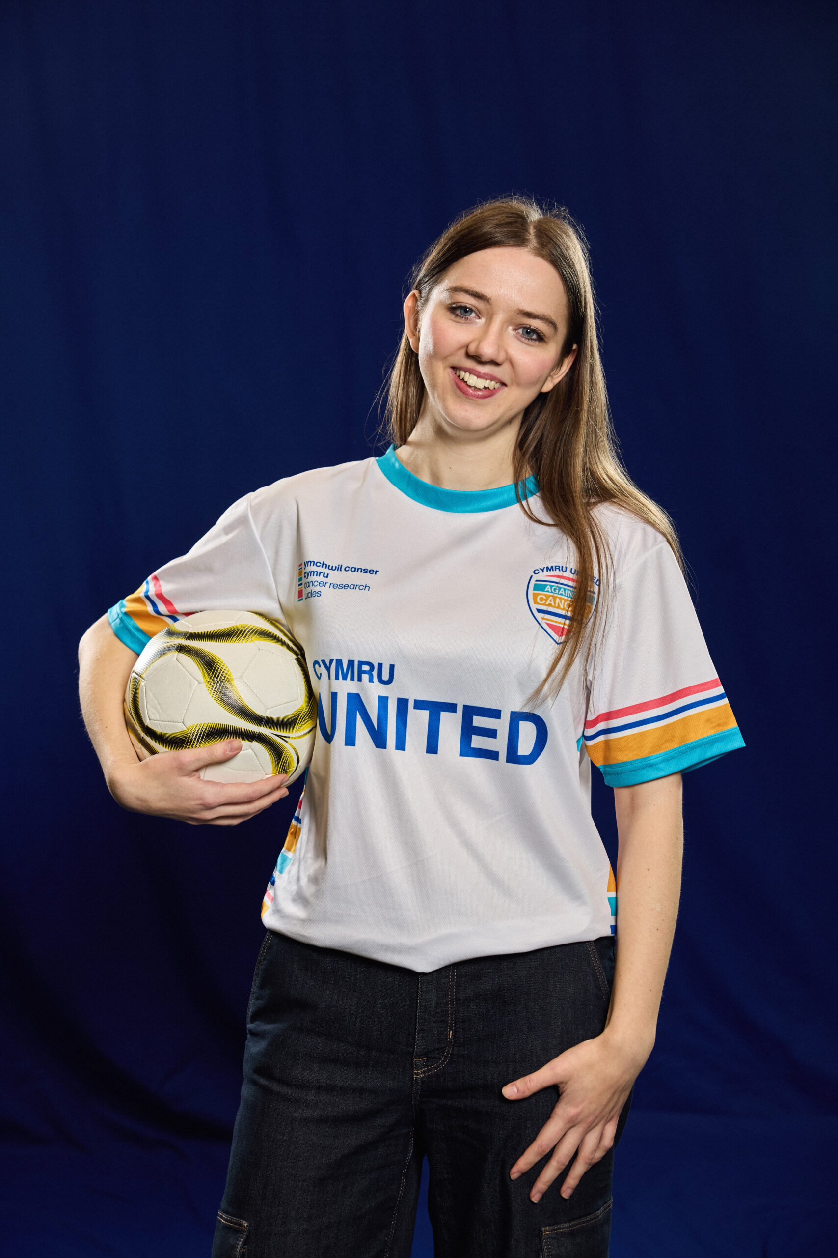 Woman holding a football looking straight ahead, smiling.