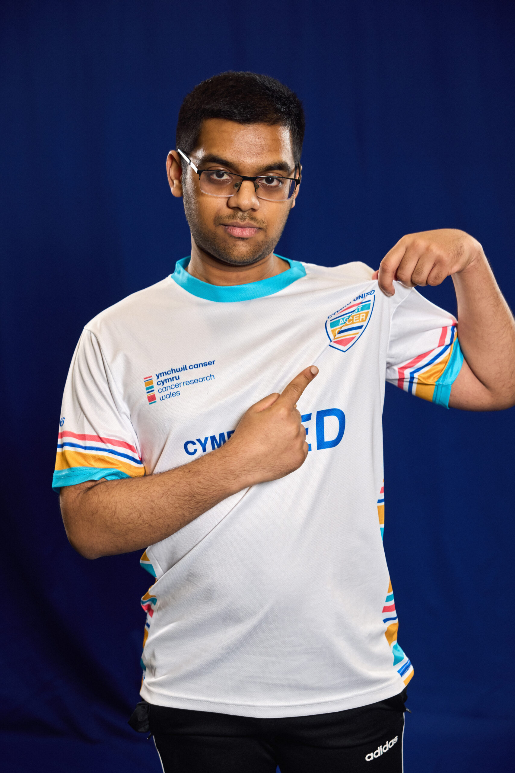 Man pointing to the Cymru United badge on his left upper chest.